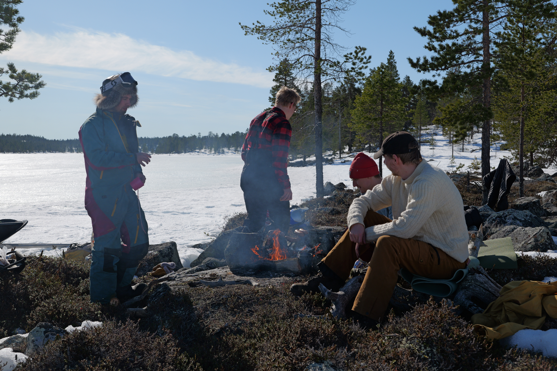 A small group sharing a campfire beside a frozen lake